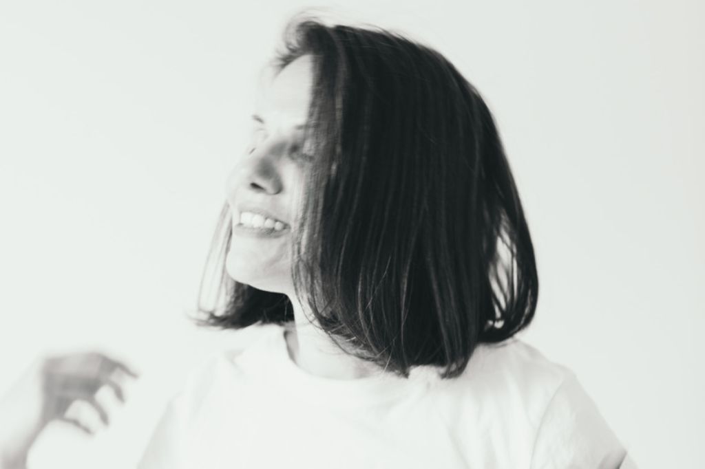 Black and white image of Kaya Ramjee smiling with eyes closed and hair slightly tousled.